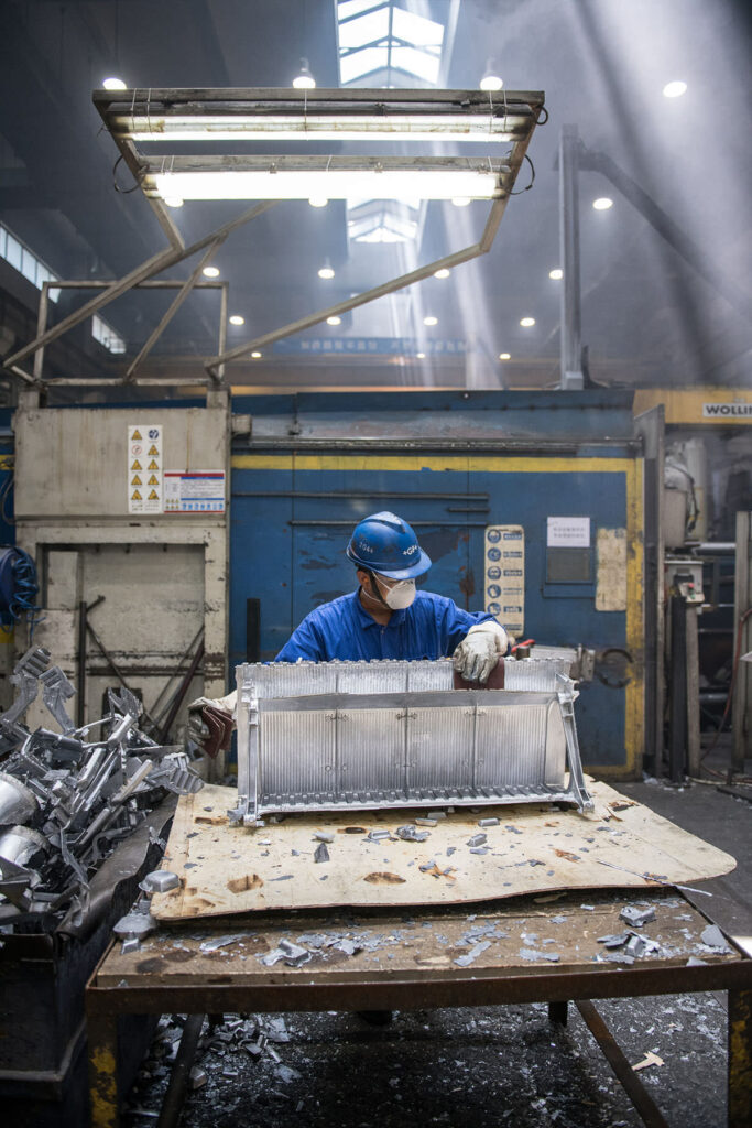 Fotografische Reportage für das Industrieunternehmen Georg Fischer +GF+ in Suzhou, China. Ein Mitarbeiter bearbeitet ein Metallelement.