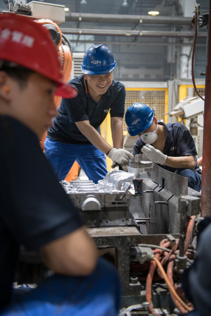 Employer Branding Aufnahme einer Gruppe von Mitarbeitern in einer Produktionshalle von Georg Fischer +GF+ in China.
