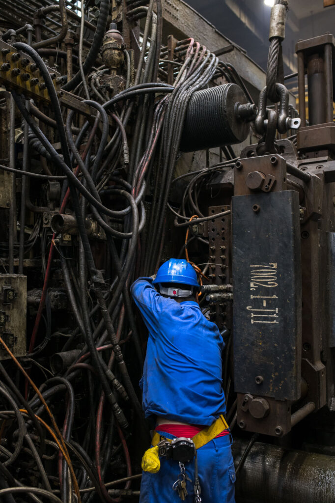 Fotografische Reportage für das Industrieunternehmen Georg Fischer +GF+ in Suzhou, China. Ein Mitarbeiter repariert eine Maschine in der Produktionshalle.