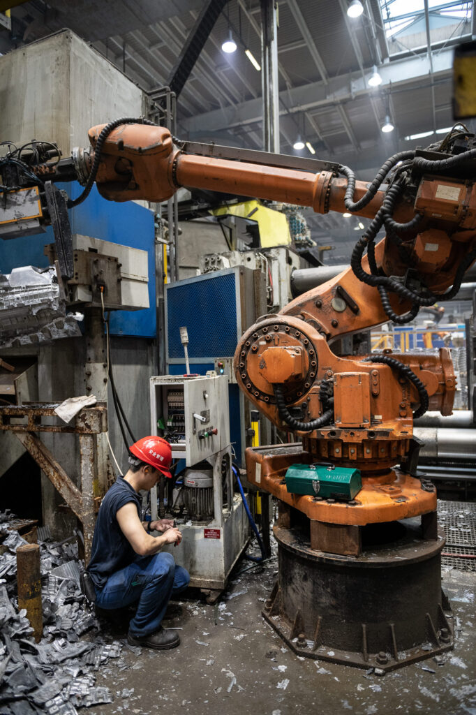 Fotografische Reportage für das Industrieunternehmen Georg Fischer +GF+ in Suzhou, China. Ein Mitarbeiter repariert einen Roboter in der Produktionshalle.