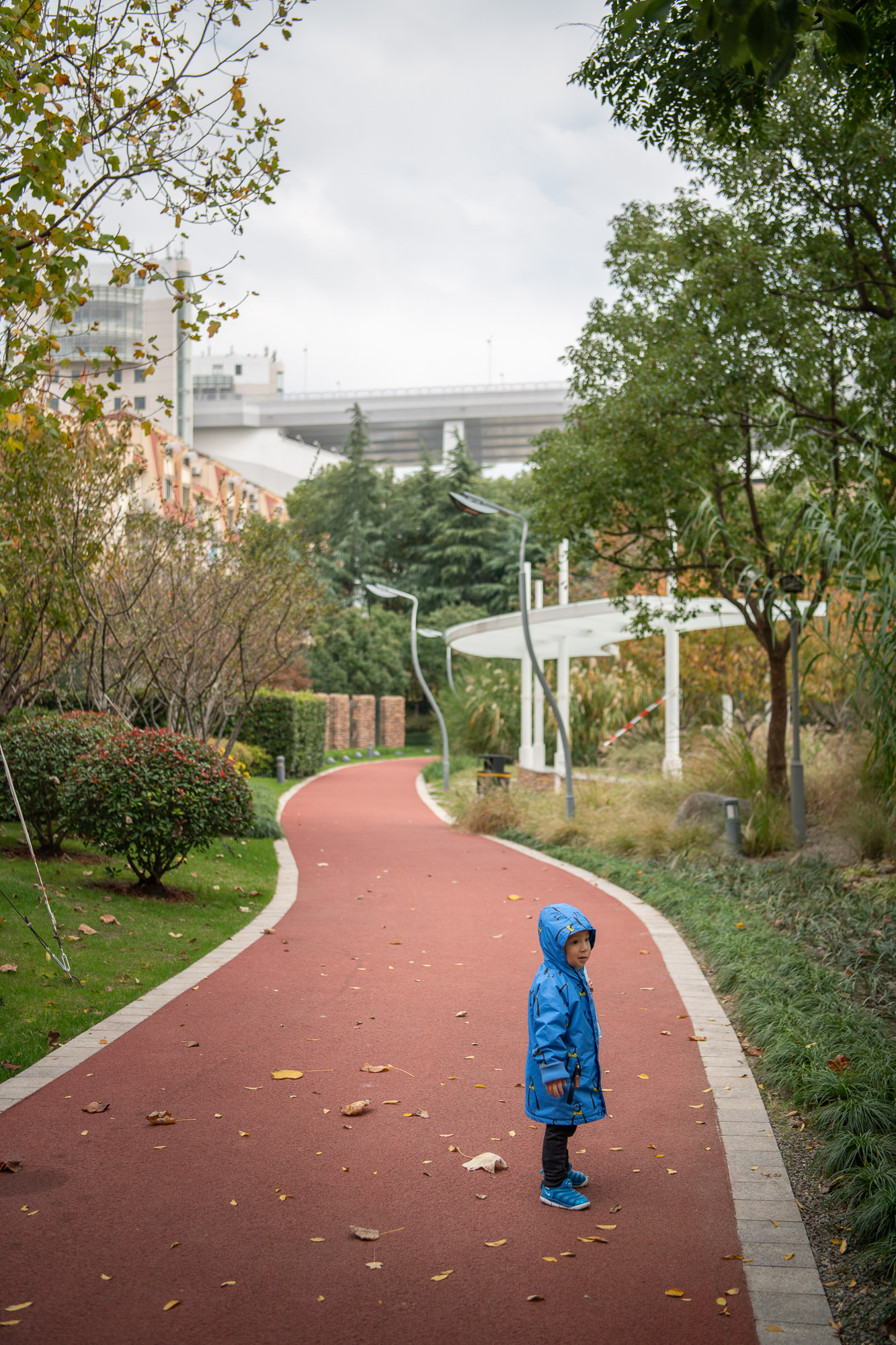 Zu Fuss entlang des Huangpu. Ein Kind wartet auf einer Joggingstrecke. Reportage und Buchprojekt über den Huangpu River in Shanghai, China.