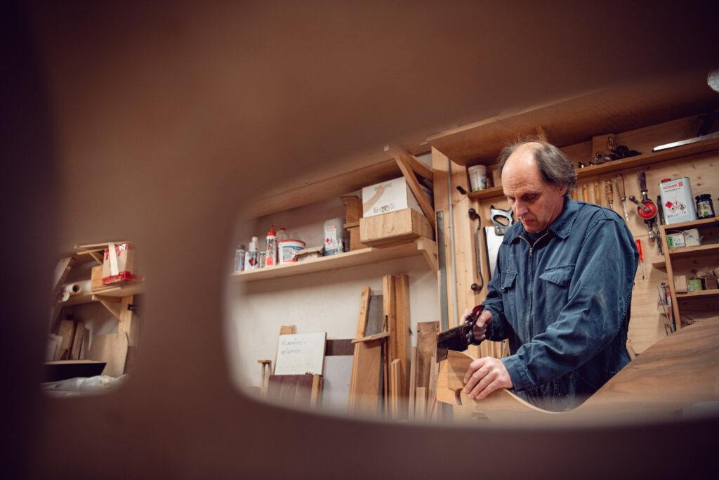 Der Harfenbauer Christoph Mani beim Sägen von Holz in seiner Werkstatt in Guggisberg FR.