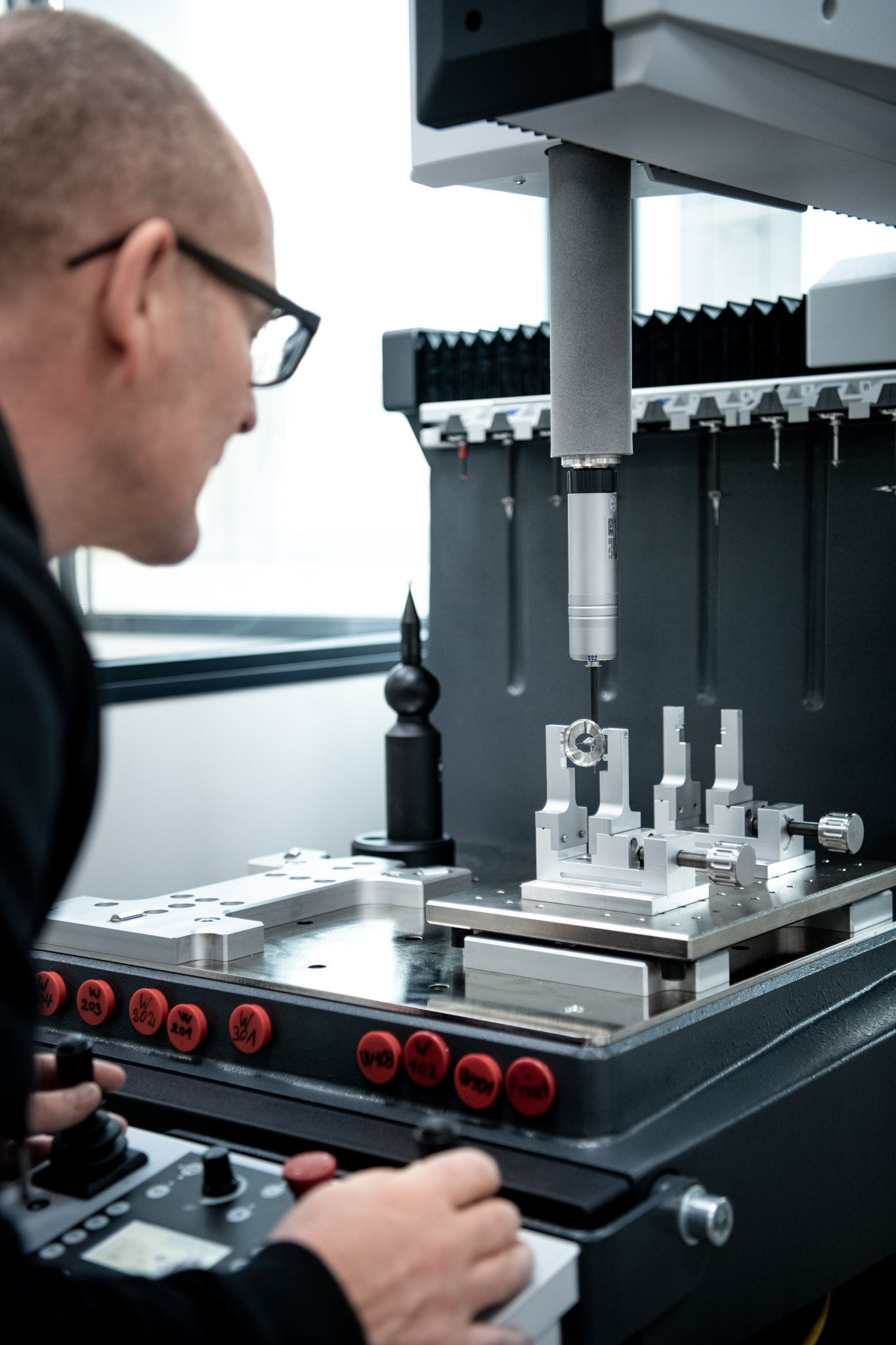 Präzises Handwerk trifft Automation in der Uhrenindustrie. Ein Mitarbeiter arbeitet an einer Maschine beim Industrieunternehmen Manufacture Wolf
